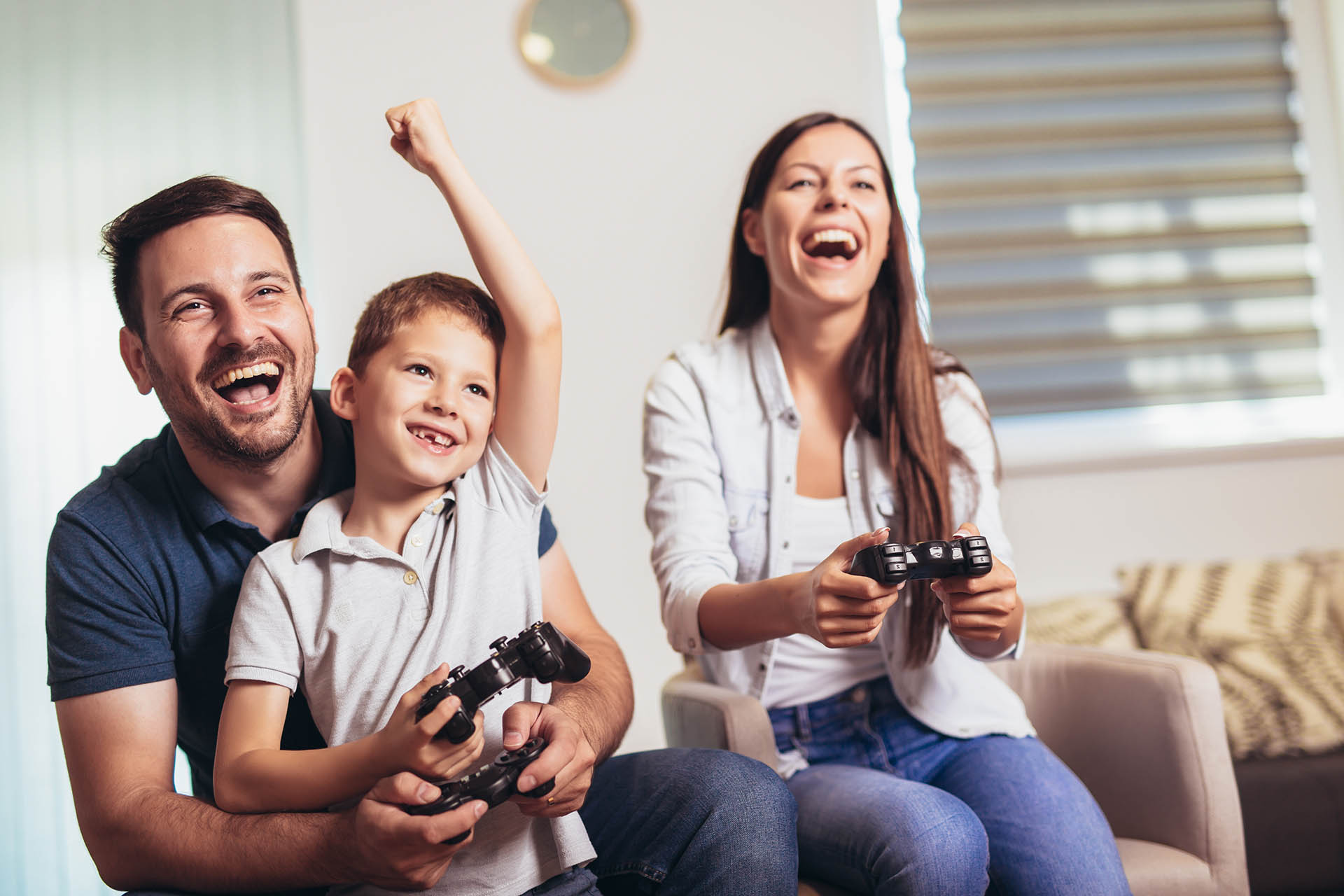 Smiling family sitting on the couch together playing video games
